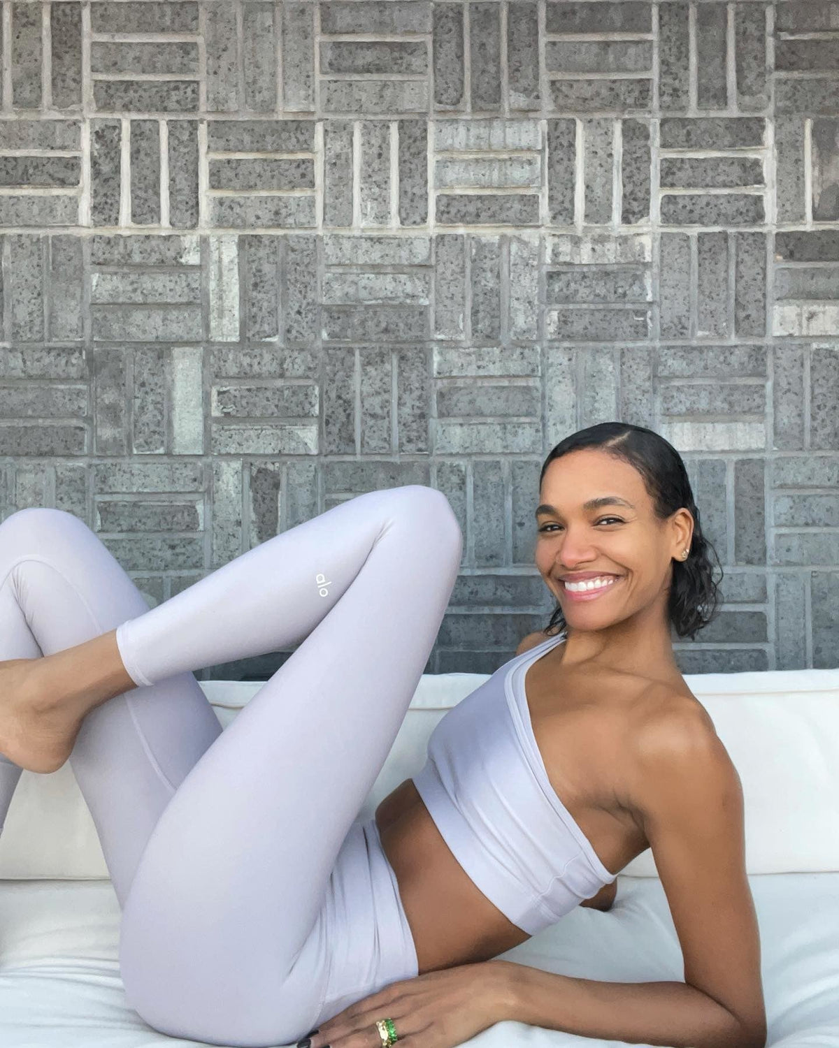 @arlenissosa wearing a light purple workout set with a one-shoulder sports bra and high-waisted leggings.  