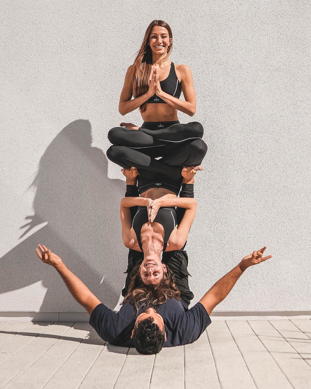 @tawnyjanae @acrowithjon and @ itscaitlinturner performing acro yoga wearing all black yoga Alo sets.  
