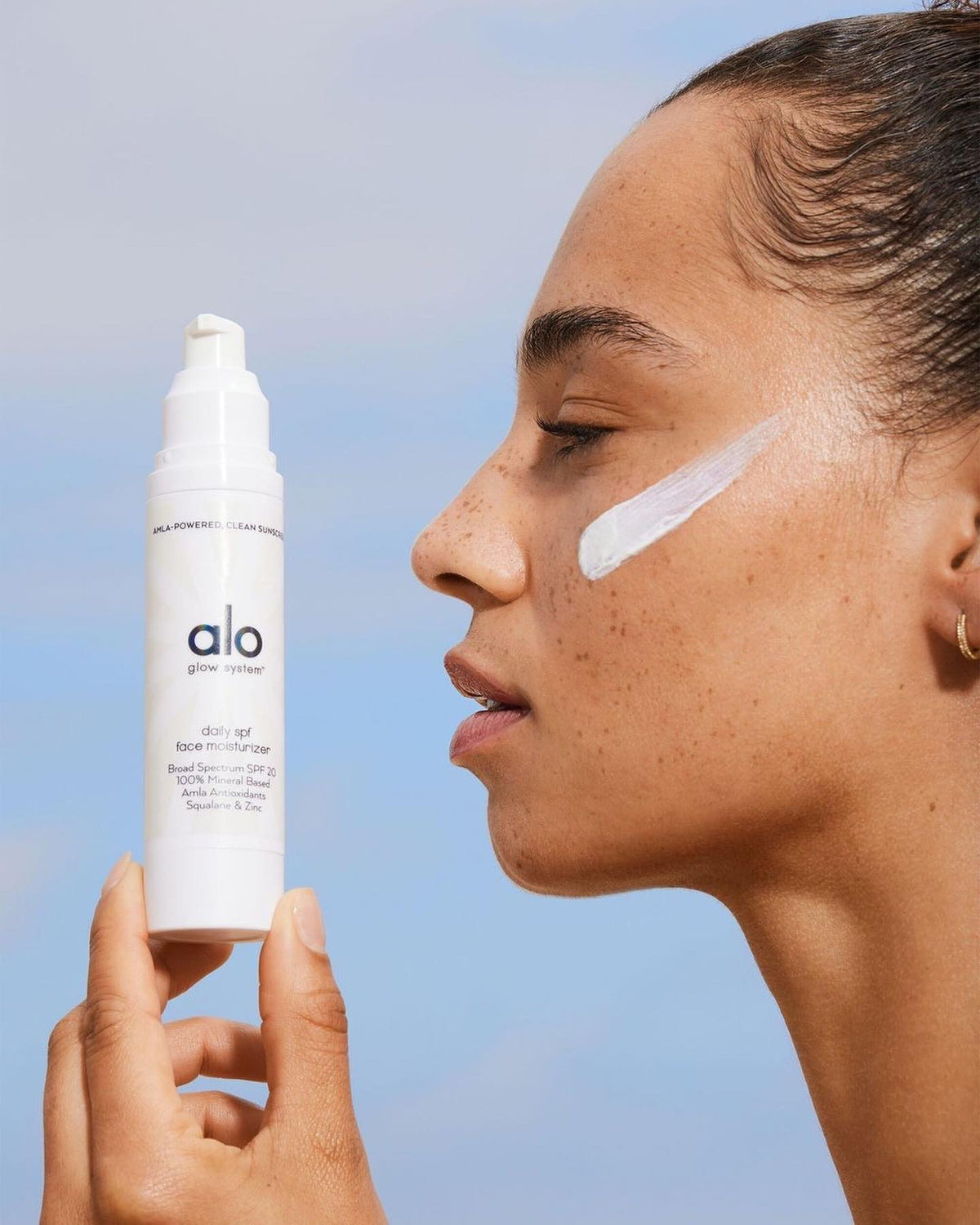 daily SPF face moisturizer on profile of woman holding bottle 