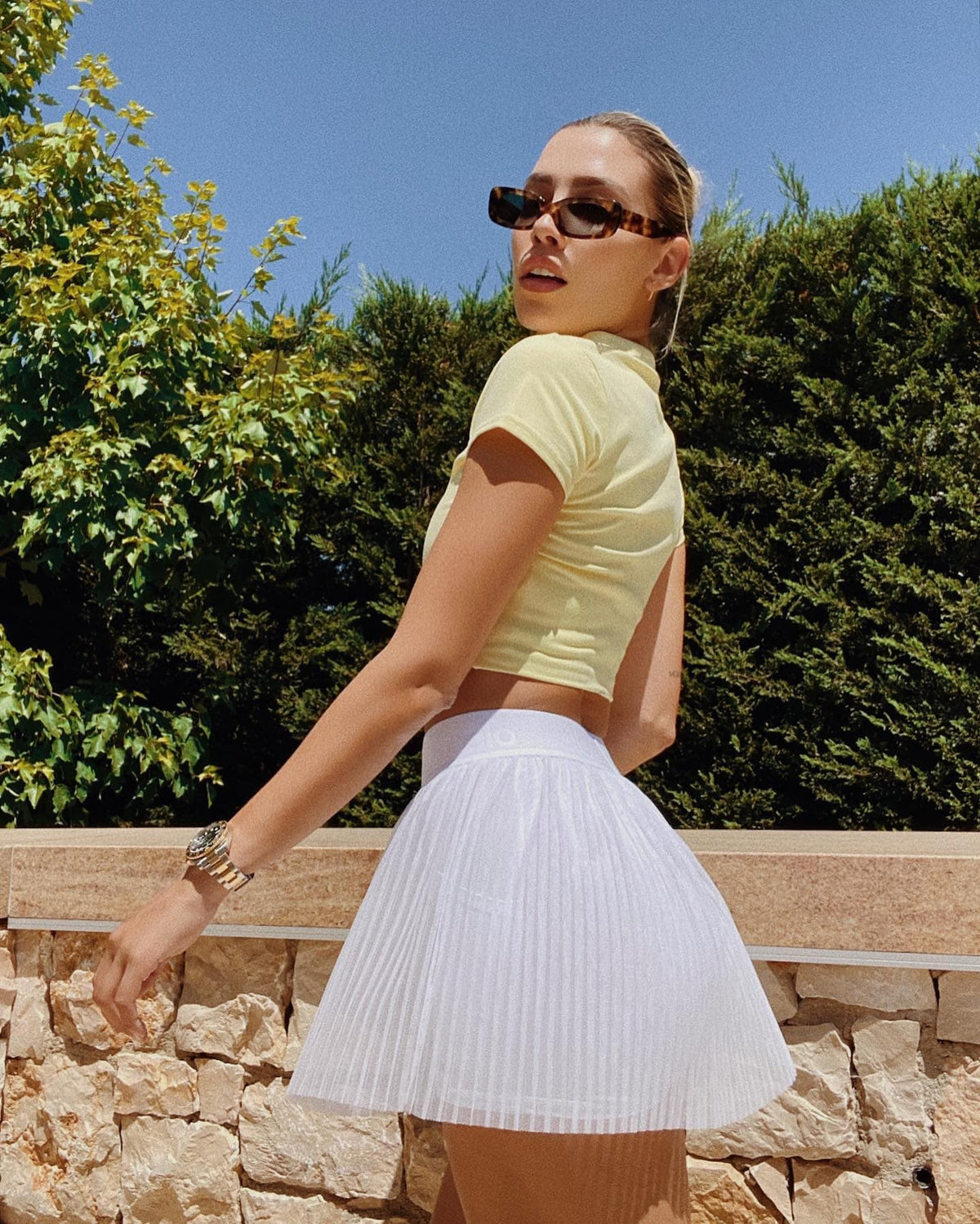 @michellesalasb wearing a Mesh Flirty Tennis Skirt in White with a Choice Polo in Buttercup while posing outside.  