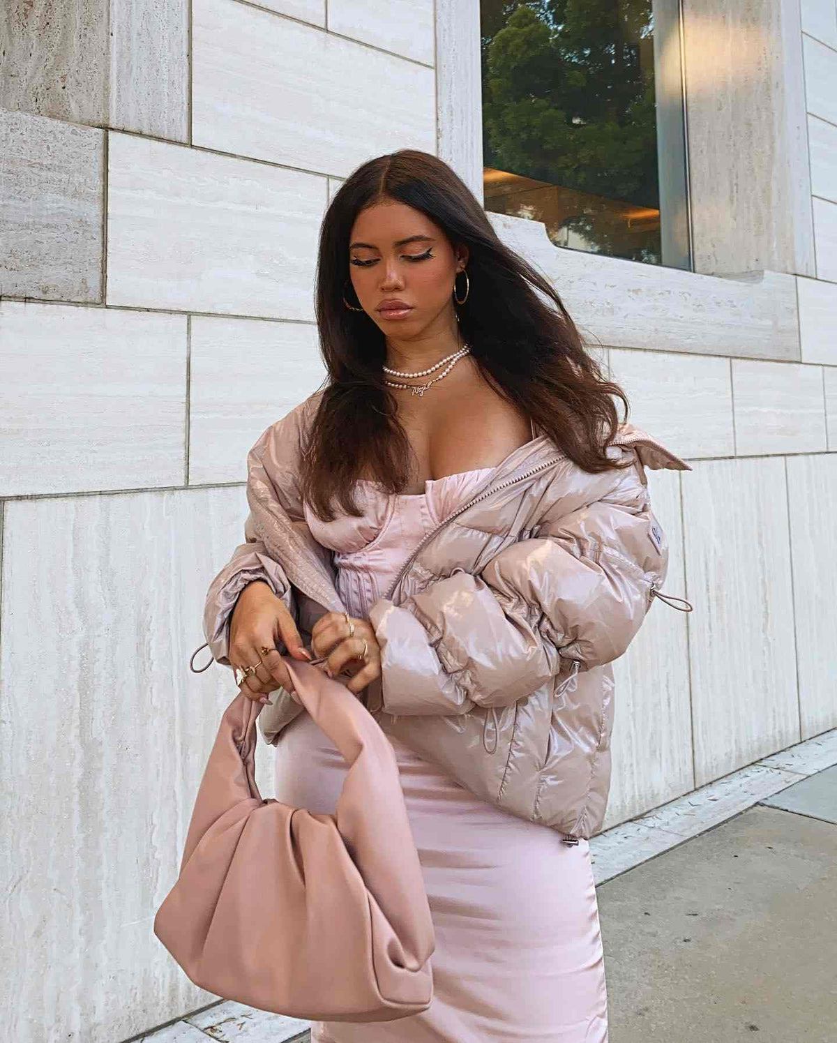@asiamonetray wearing the Stunner Puffer Jacket in Dusty Pink on top of a light pink gown and mauve colored bag for a stunning monochromatic glamour look.  